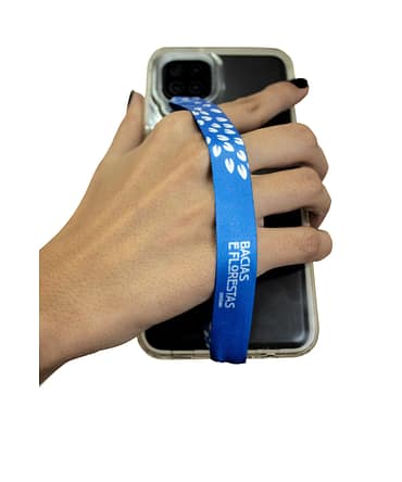 Cordão de segurança para celular com uma estampa de folhas brancas em um fundo azul. O logo da Ambev - Bacias e Florestas também está presente em branco na estampa