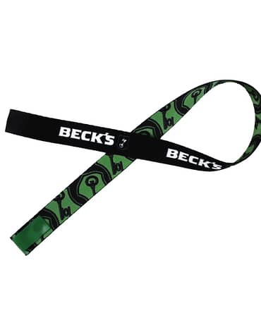 Cordão de segurança para celular da marca Becks. Um lado apresenta a cor preta com o logotipo Becks escrito em branco, enquanto o outro lado é verde com ilustrações de chaves em preto.