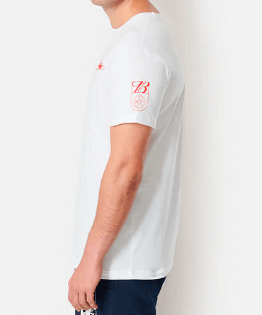Modelo de perfil vestido uma camiseta branca da Budweiser. A manga da camiseta tem uma estampa que mostra um globo terrestre e a letra "B", ambos em vermelho.