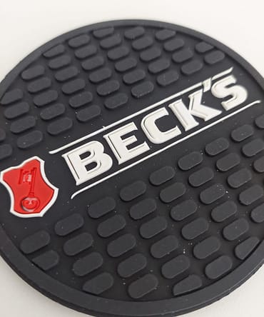 Descanso de copo na cor preta com letras do logotipo escrito becks em detalhes branco e vermelho