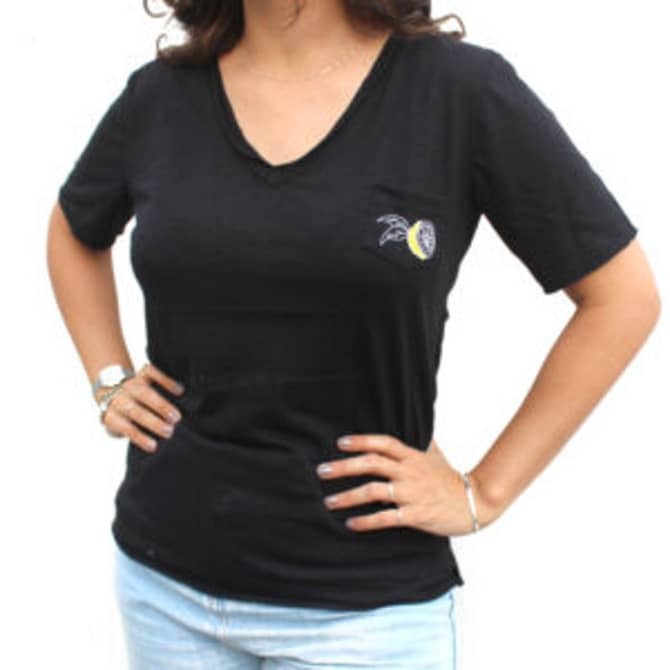 Camiseta preta da marca Corona com um limão estampado no bolso, localizado na parte superior esquerda da camiseta.